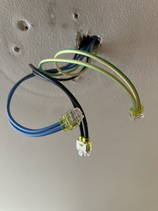 Kablar vid ett lampställe där två N-kablar och två L-kablar är anslutna med klämmor och hänger från ett hål i taket.