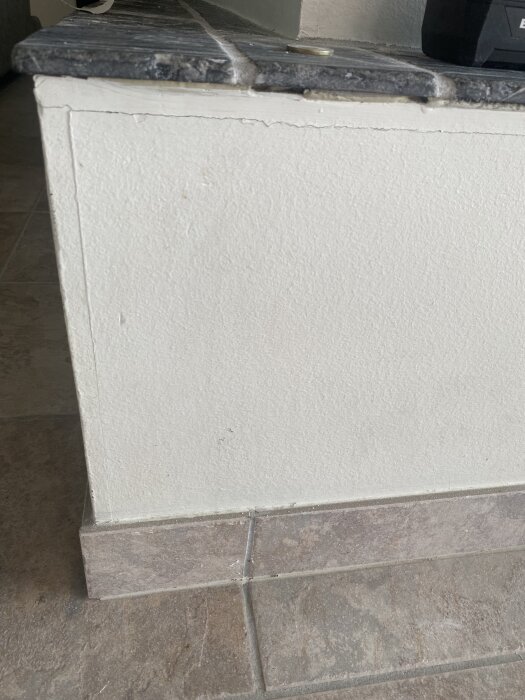 Vägg med spricka vid hörn, kakel ovanpå. Diskuteras om remsa eller spackling behövs för målning utan framtida sprickor.