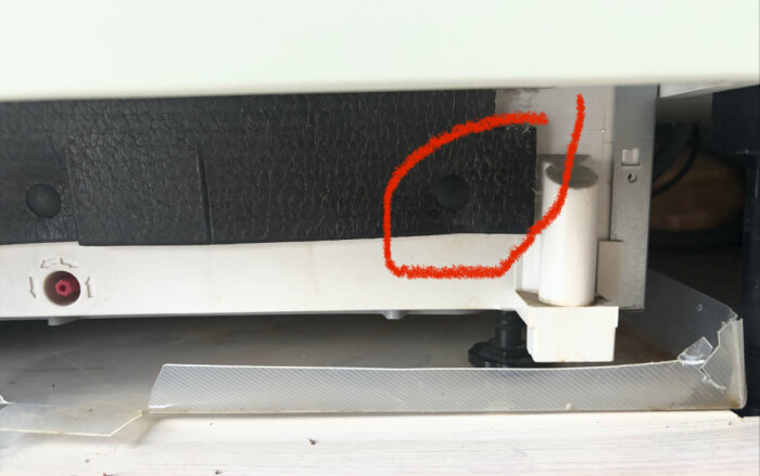 Närbild av diskmaskinens underdel med en röd markering runt området där vattnet läcker vid ena foten.