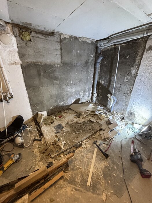 Renoverat badrum med rivna plattor och verktyg på golvet, trasiga bitar av gammal platta syns på platsen för tidigare oljetank.