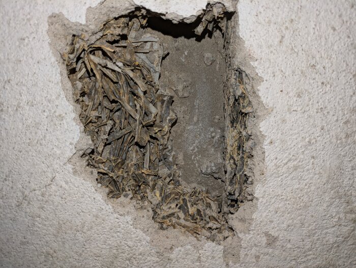 Vassmatta bakom skadad puts under yttertrappa från 1961, synlig efter borttagen puts.