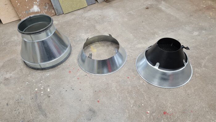 Tre nybyggda metalltrattar i varierande storlekar ligger på ett verkstadsgolv, klara för att användas i svetsutsugstestning.
