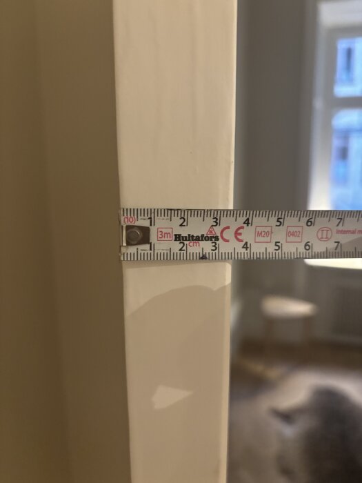 Måttband som mäter dörrens bredd till 35mm i ett hem.