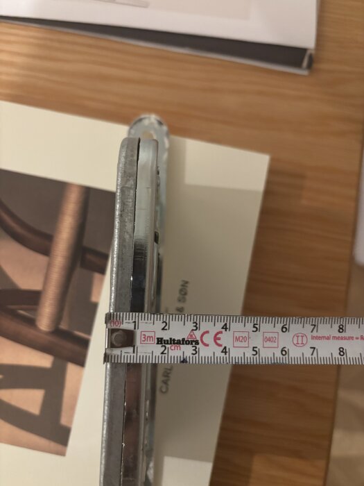 Mätband visar bredden på en dörr som mäter cirka 35 mm, med fokus på monteringen av en låscylinder.