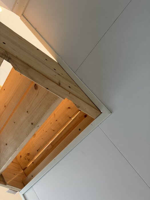 Träbalkar och vitmålade väggar, förberedelser för montering av nytt räcke i ett renoveringsprojekt i hemmet.