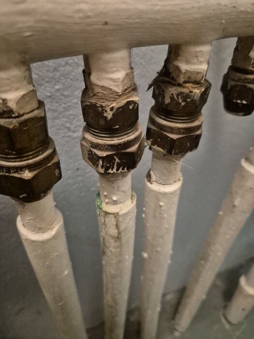 Rörledning med läcka, vit prisolrör med metallkopplingar och synlig vattenläcka i hemreparation.