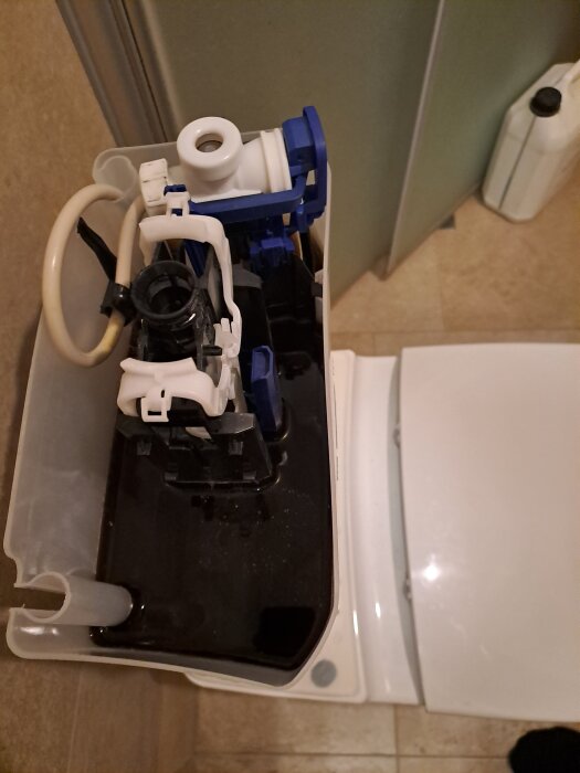 Öppen toaletttank med svart beläggning, sannolikt mangan, vilket oroar ägaren för möjliga skador och igensättning på sikt.