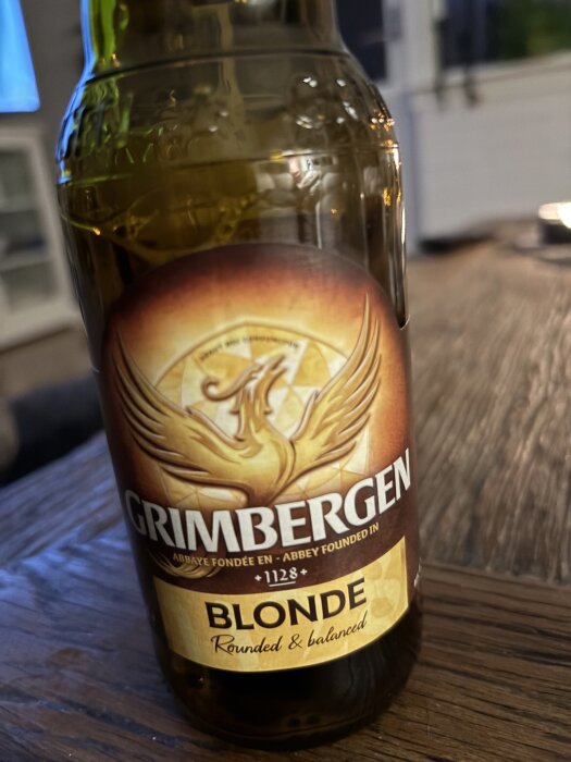 Flaska med Grimbergen Blonde öl stående på ett bord.
