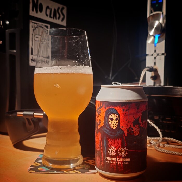 Glas med ljus öl bredvid en burk med färgglad etikett i en musikstudio-miljö.