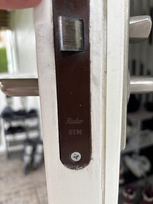 Ytterdörrlås av märket Ruko SYM i närbild, monterat på en vitmålad dörr.