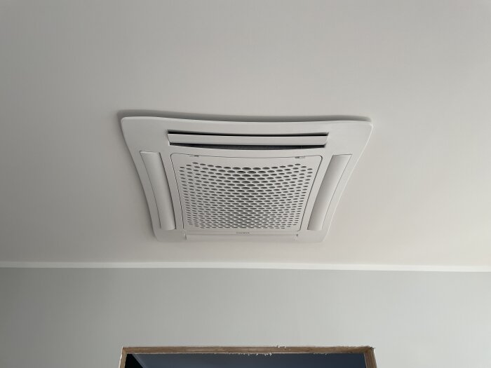 Inbyggd takmonterad luftkylare med ventilationsgaller synligt i ett rum.