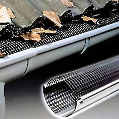 Sil med nät i en hängränna under tak med tegelpannor, avsedd för att förhindra att löv och skräp blockerar avrinning.