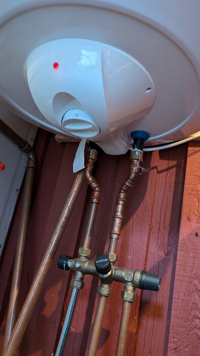 Varmvattenberedare med kopparrör och ventil för inkommande vatten, stängd med texten "Avstängd". Röd lampa lyser på beredaren.