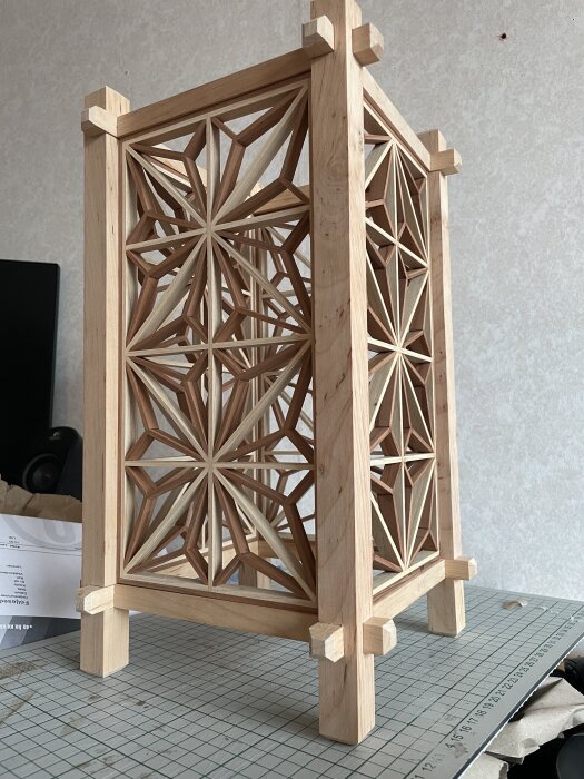 Trästruktur med intrikat geometriskt mönster på en byggplatta, verkar vara en del av ett dekorativt projekt.