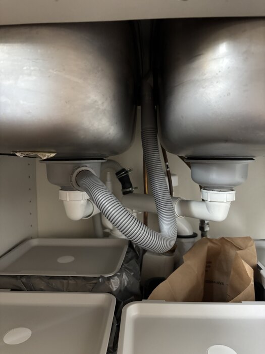 Slangar och avloppsrör under dubbelho i köksskåp.