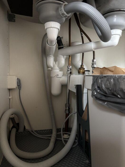 Under an image of sink plumbing with hoses and pipes under a kitchen sink.