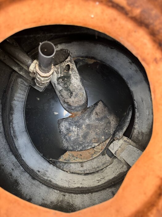 Illustration av gammal brunn med vatten, flera rör och en del skräp synliga, indikerar pågående underhållsproblem.