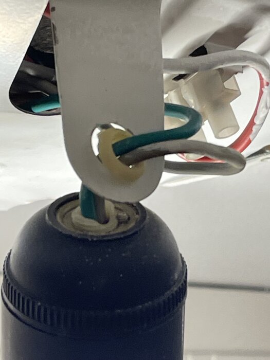 Närbild av elektricitetssockel med exponerade kablar, där en gummiringen är sliten. Lamphållare behöver justeras för korrekt funktion.