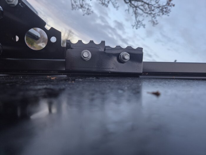 Närbild av monterat snörasskydd på klicktak, visar fästning med bultar och placering i förhållande till plåtens kant och veck.