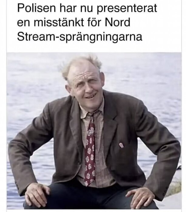 En man i kavaj och slips sitter vid vattnet, ovanför står texten "Polisen har nu presenterat en misstänkt för Nord Stream-sprängningarna".