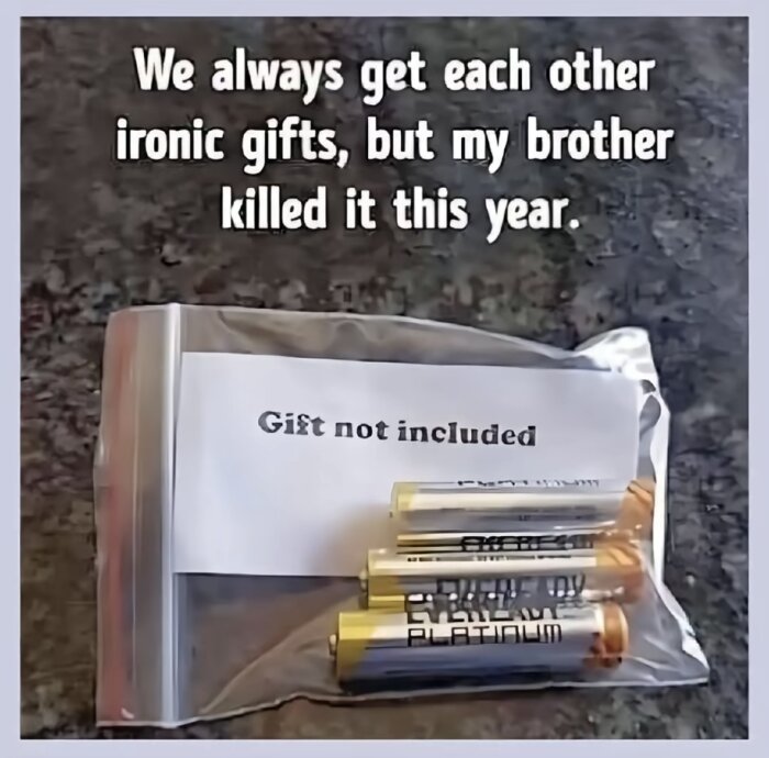 Zip-påse med batterier och en lapp med texten "Gift not included" på ett bord.