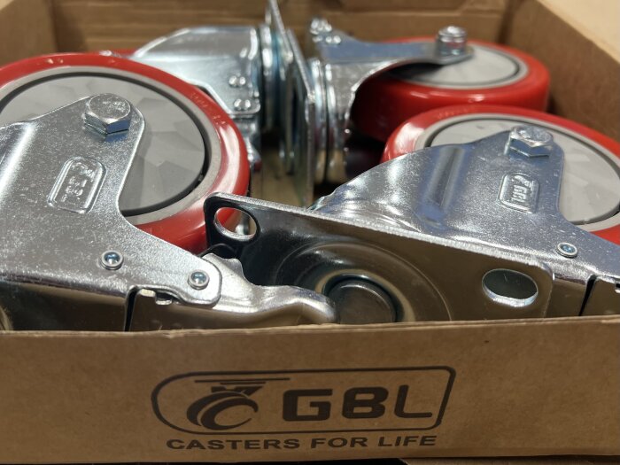 Kraftiga hjul från GBL med röda detaljer i en kartong. Texten "Casters for life" syns på lådan.