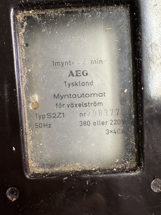 Gammal myntautomat från AEG för växelström, med specificerade spänningar och strömstyrkor, hittad hos svärföräldrarna och redo för upputsning.