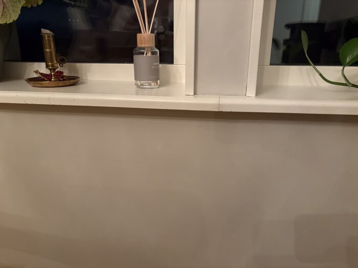 Fönsterbord med dekorationer, diffusor och växt, planerat för montering av en dekorlist undertill.