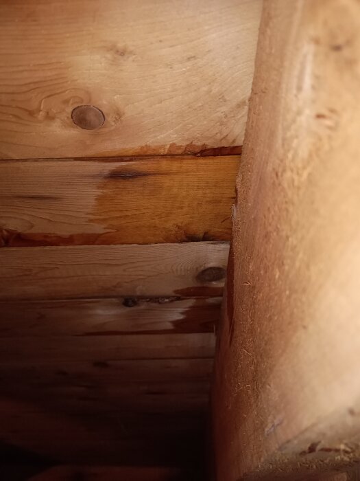 Fuktskadad takpanel med mörka fläckar på grund av dåliga skarvar och vattenläckage, synliga träytor och spår av vatteninträngning.