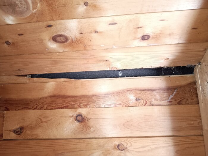 Spricka i taket med synliga dåliga skarvar i takduken, träbitar saknas och råspont är skadad.