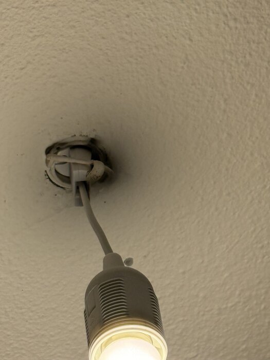 Lampa upphängd i taket med sladd, installerad och tänd.