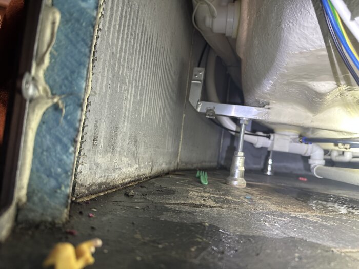 Insidan av en inbyggd hörn-spabadskonstruktion med rör och en blå XPS-skiva synlig under badkaret.