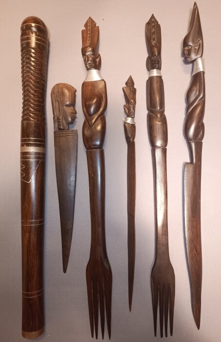 Fem träslevar och gafflar med snidade huvuden och detaljer som verkar vara afrikansk konst, förmodligen importerade från Kenya på 1960- eller 1970-talet.