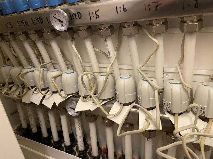 Värmefördelningssystem med flera rör och ställdon, märkta med nummer och kopplade till varandra.