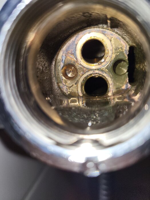 Närbild av inuti en duschblandare med tre synliga rör och en del av metallen borta, vilket orsakar läckage från vredet.