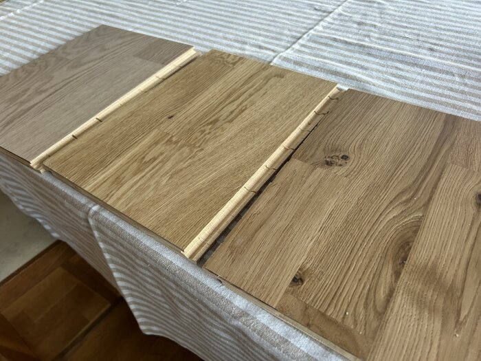 Tre parkettprover i olika tränyanser ligger på ett randigt bord.