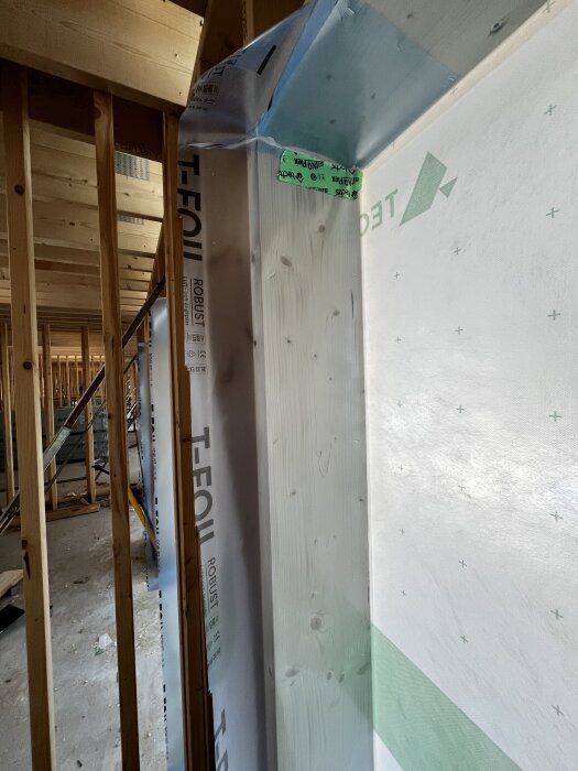 Plastad fönsterram med monterad ångspärr och synligt träverk, del av pågående byggprojekt.