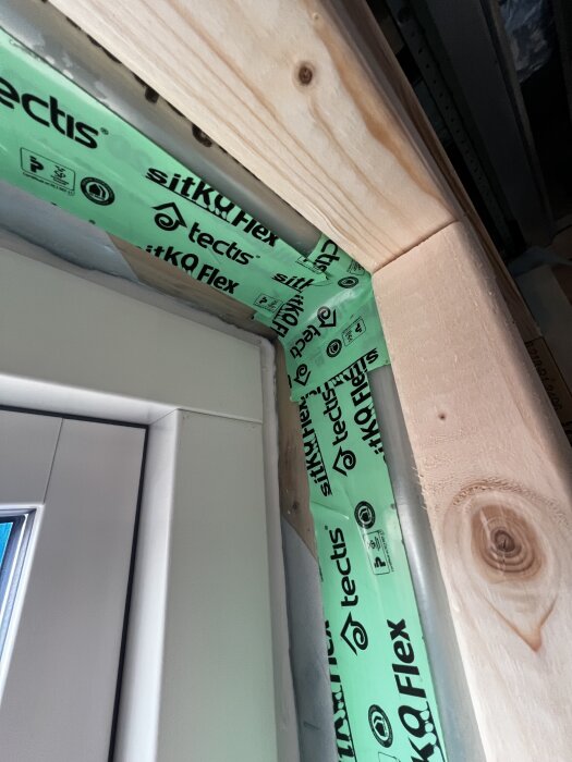 Närbild på ett fönster med monterad ångspärr, täckt med grön Tectis tejp mellan karm och stomme.