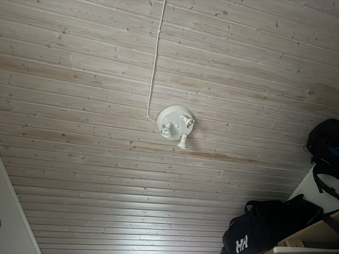 Innertak i trä med mörkare fläckar synliga, taklampa monterad centralt.