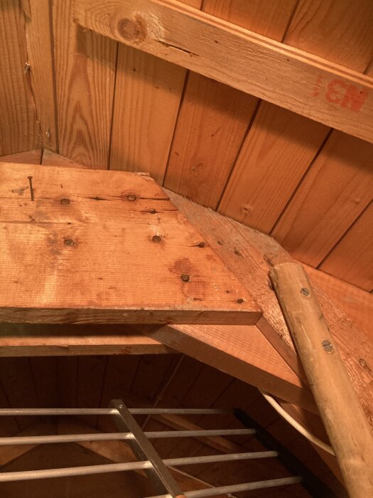 Trätak i vindsutrymme med synliga brädor och spikar; tecken på slitage men torrt, troligen oroväckande för byggprojekt.