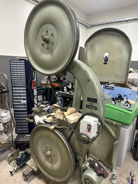 Två gamla bandsågar, en Jonsereds och en Värnamo, står i ett verkstadsutrymme med liggande träbitar och verktyg runt dem.