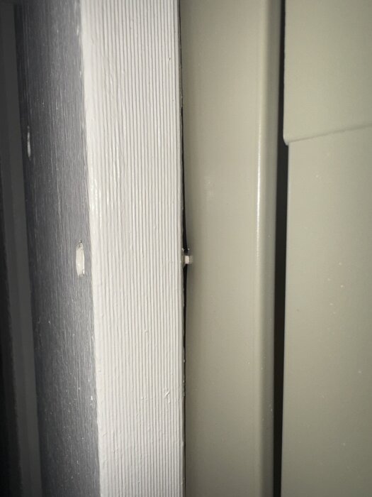 Närbild på ett aluminiumbeklätt fönster där fodret är spikat genom aluminiumet och panelen, vilket orsakar oro för fuktskydd och garantier.