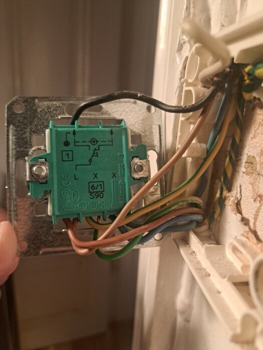 Elektrisk brytare med flera anslutna ledningar i olika färger inklusive brun, blå och grön/gul.