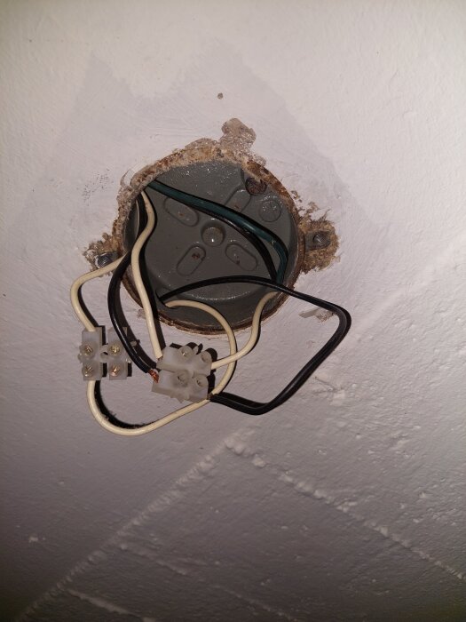 Öppen kopplingsdosa i tak med flera elektriska sladdar i olika färger som behöver organiseras för installation av ny taklampa.
