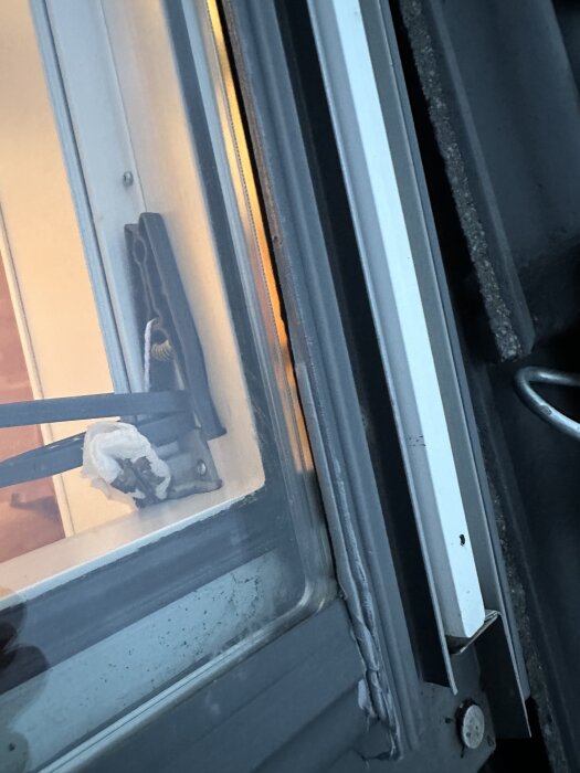 Närbild på ett takfönster med tätning längs kanten, skruvar synliga i ramen. Tätningen verkar nyapplicerad för att förhindra läckage.
