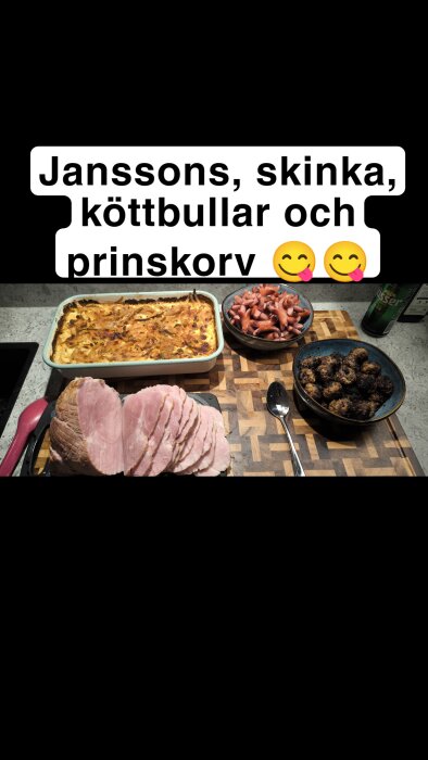 Julbord med Janssons frestelse, skivad skinka, köttbullar och prinskorv på en skärbräda.