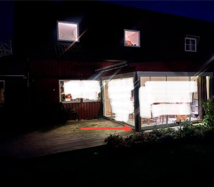 Uterum med glasväggar och trädäck, röd pil pekar mot hörn där fuktskador uppstått.