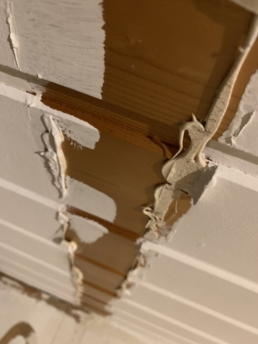Tak med kvarvarande limrester efter fejk-bjälkar, synliga skador och försök att avlägsna limmet.