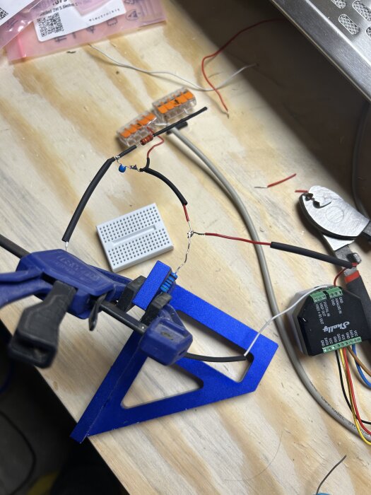 Elektronisk uppsättning på ett bord med resistorer och kablar kopplade till en Shelly-enhet för att läsa utsignal från en fläkt.