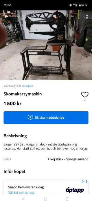 Antik Singer skomakarsymaskin i ett garage, står på cementgolv bredvid däckstaplar och verktyg, med detaljerad utsmyckning.